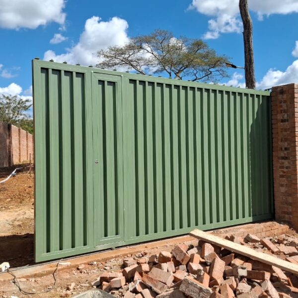 Aloe green steel driveway gate with pedestrian wicket door set in a face brick boundary wall, Umwinsidale