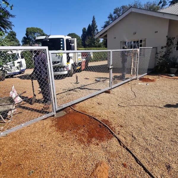 Galvanised diamond mesh fence and gate being installed in a Borrowdale yard, Harare