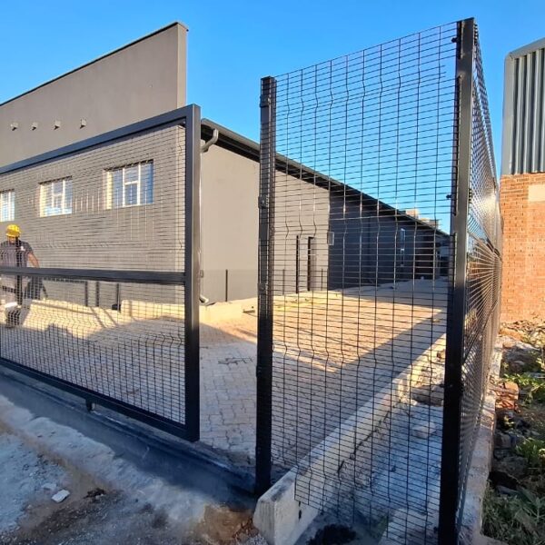 Black clearview mesh sliding gate and matching security fence panel installed at a commercial yard entrance