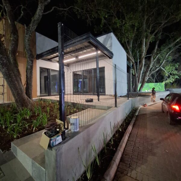 Black clearview mesh fencing on a low wall outside a modern commercial building at night