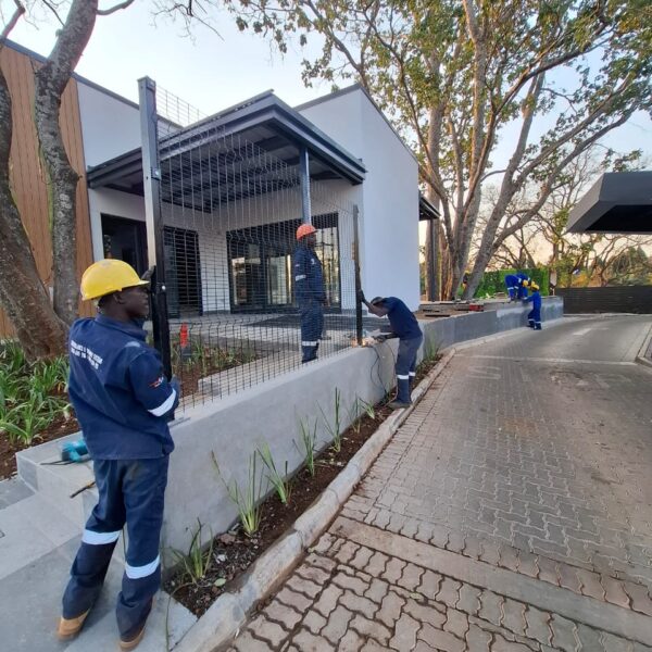 Installation team fitting black clearview mesh fencing outside a modern commercial building