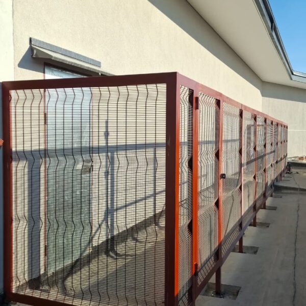 Steel framed clearview mesh screen in red oxide primer along a commercial building wall before final coating