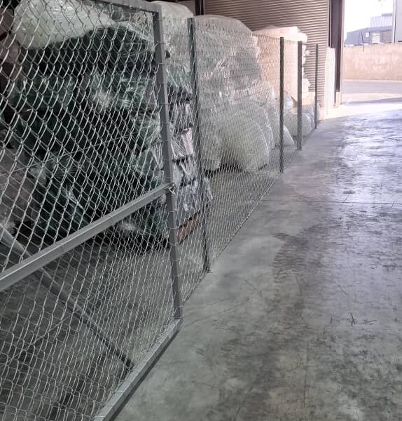 Galvanised diamond mesh partition fence separating a storage bay from the aisle inside a warehouse