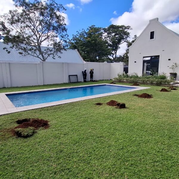 Swimming pool and lawn with freshly dug post holes before pool safety fence installation, Greendale