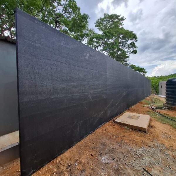 Black shade cloth screening stretched along a site boundary frame in Zimbabwe